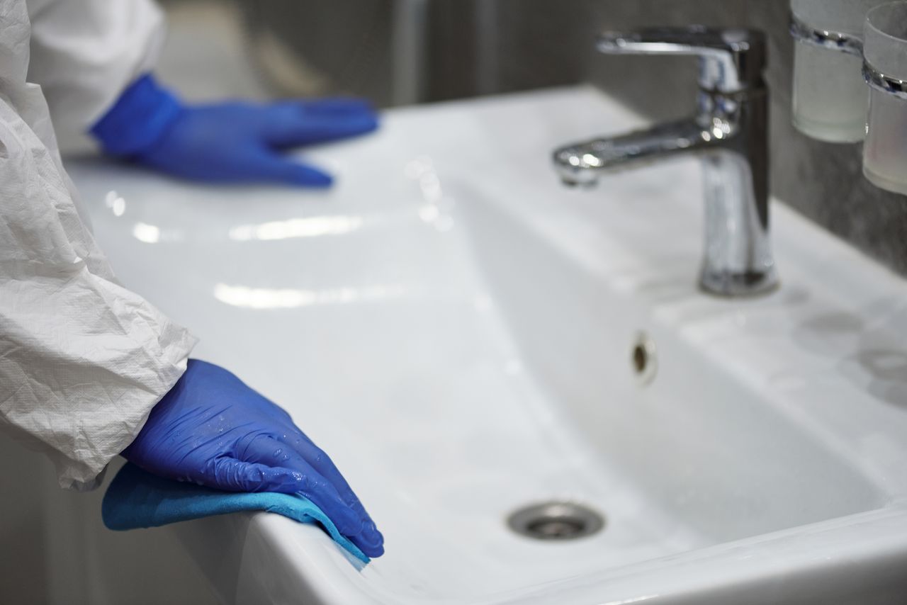 services-03 Gros plan d’un professionnel ganté nettoyant un évier pour des raisons d’hygiène.