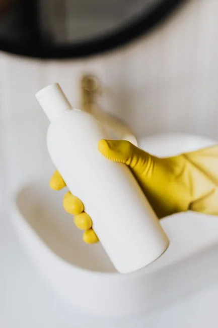 about-us-02 Des mains gantées de jaune nettoient un mur à l’aide d’une éponge et d’un vaporisateur.